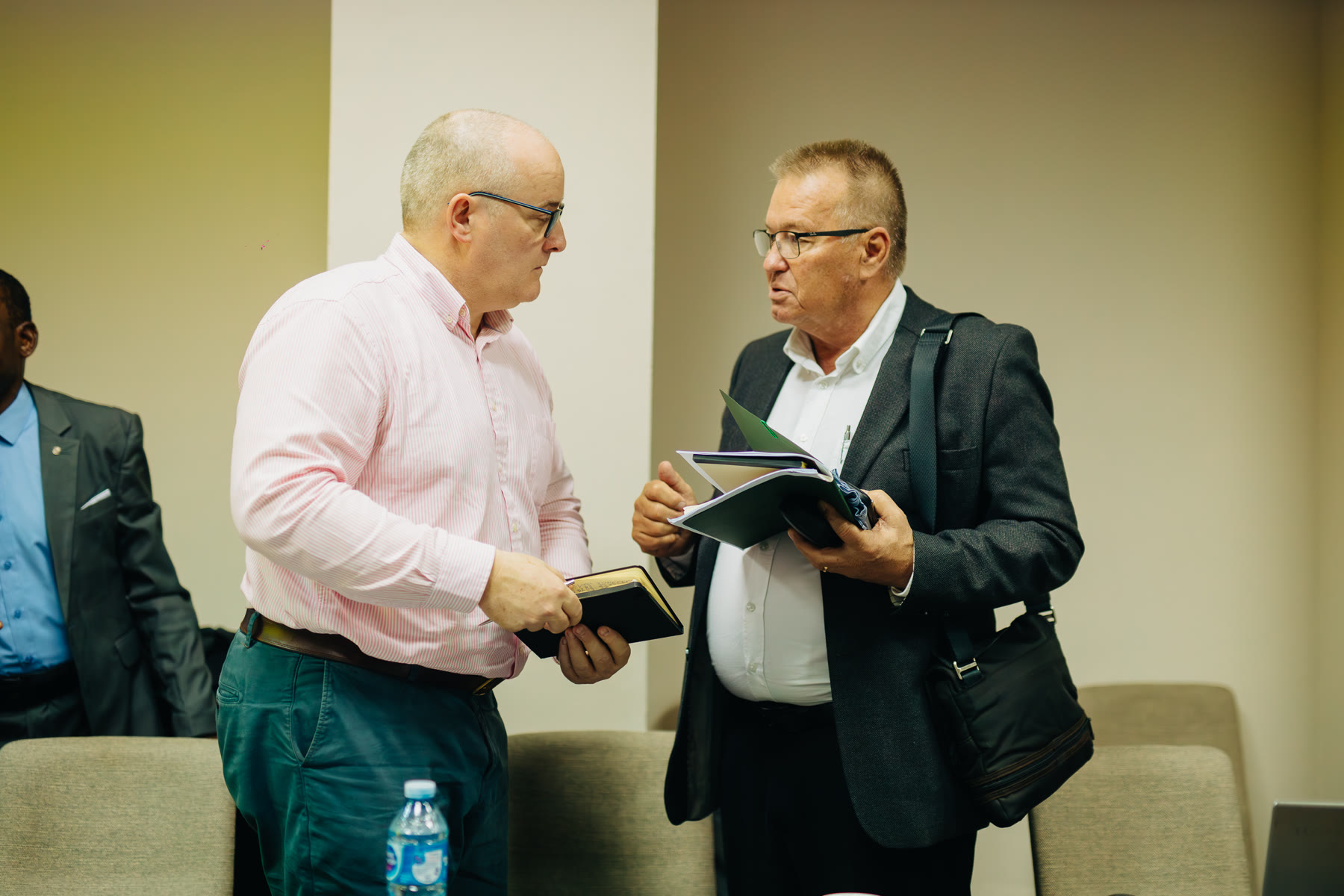 Two delegates comparing notes while standing.